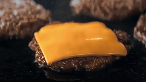 Cheese melting onto a smashed beef patty on the grill