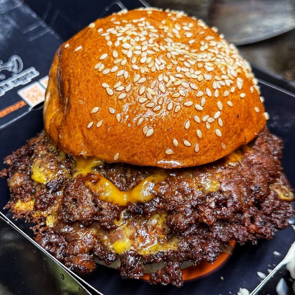 A double smash burger with crispy edges and melted cheese under a sesame brioche bun